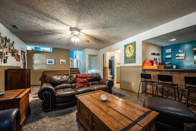 living area featuring visible vents, a bar, stairs, a textured ceiling, and carpet floors