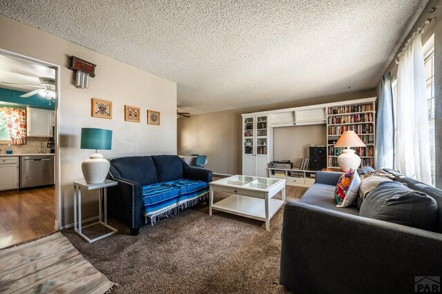 living room with a textured ceiling, ceiling fan, and dark wood finished floors