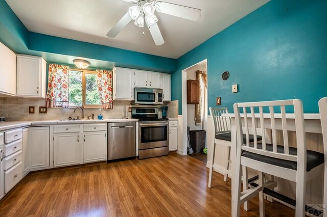 kitchen featuring white cabinets, decorative backsplash, stainless steel appliances, and light countertops