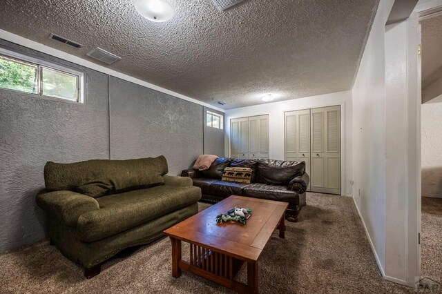 living room featuring a textured ceiling, a textured wall, carpet flooring, visible vents, and baseboards