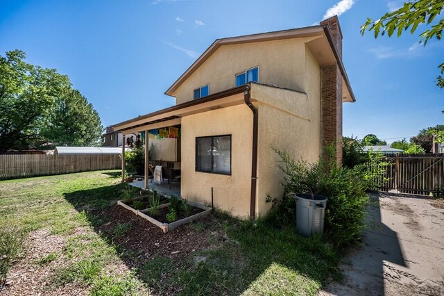 view of side of home with a yard, fence, and stucco siding