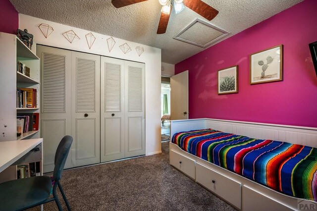 bedroom with attic access, ceiling fan, dark colored carpet, a textured ceiling, and a closet