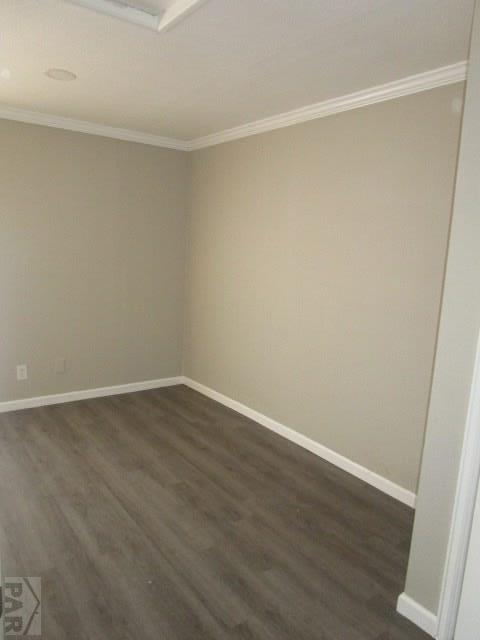 spare room with dark wood-style floors, ornamental molding, and baseboards