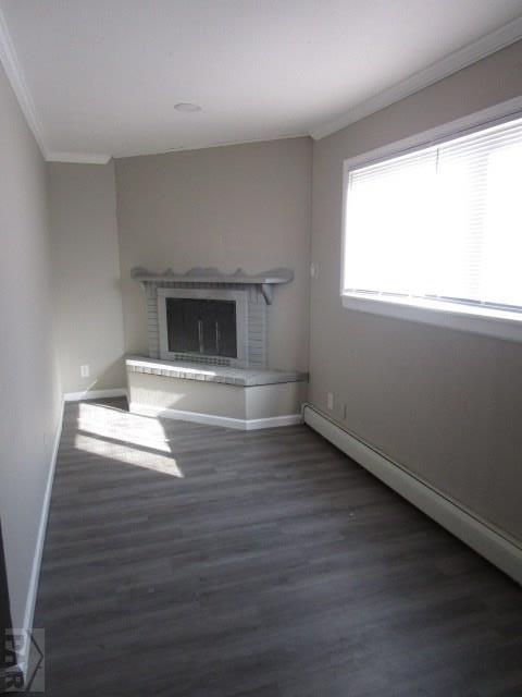 unfurnished living room with baseboards, dark wood finished floors, a baseboard radiator, crown molding, and a fireplace