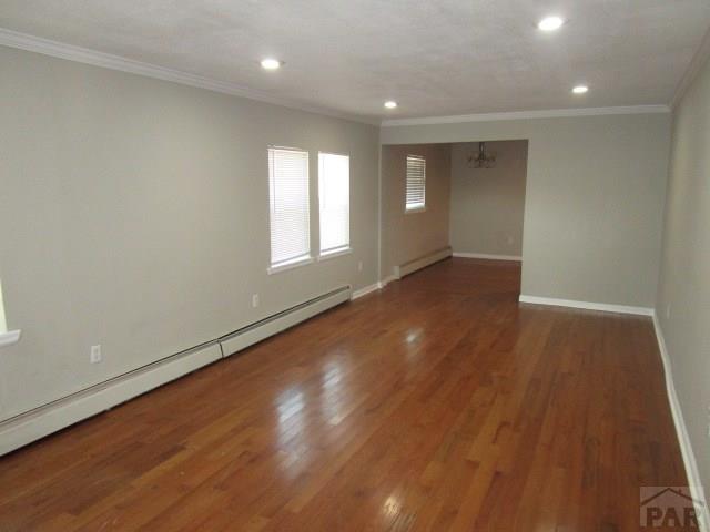 unfurnished room featuring crown molding, a baseboard radiator, a baseboard heating unit, dark wood-type flooring, and baseboards