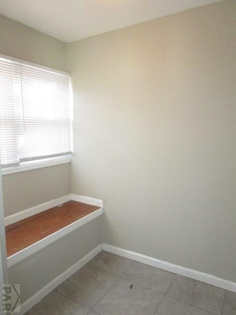 unfurnished room with tile patterned flooring and baseboards