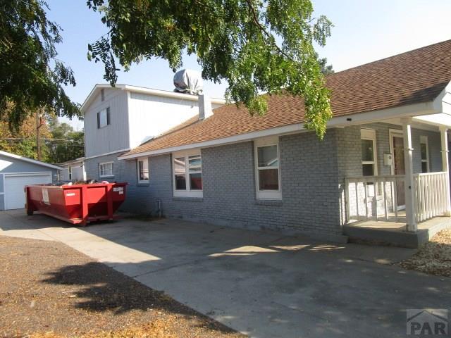 view of side of property featuring a garage, brick siding, an outdoor structure, and roof with shingles