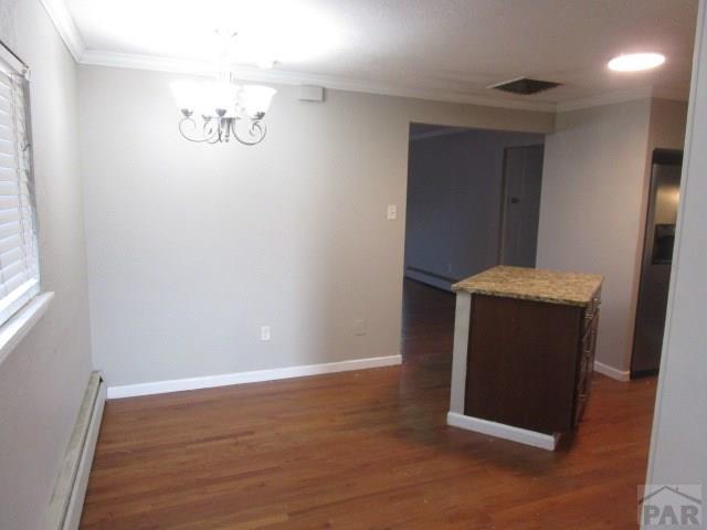 interior space with baseboards, stainless steel fridge with ice dispenser, ornamental molding, dark wood-type flooring, and a chandelier