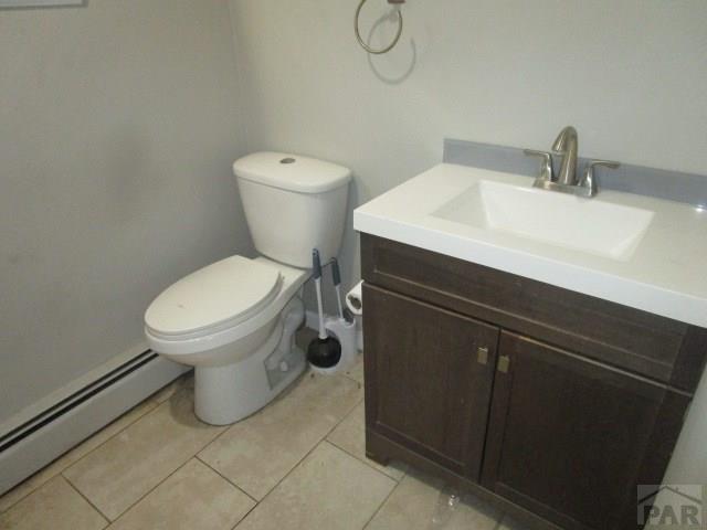 half bath featuring toilet, a baseboard radiator, tile patterned flooring, and vanity