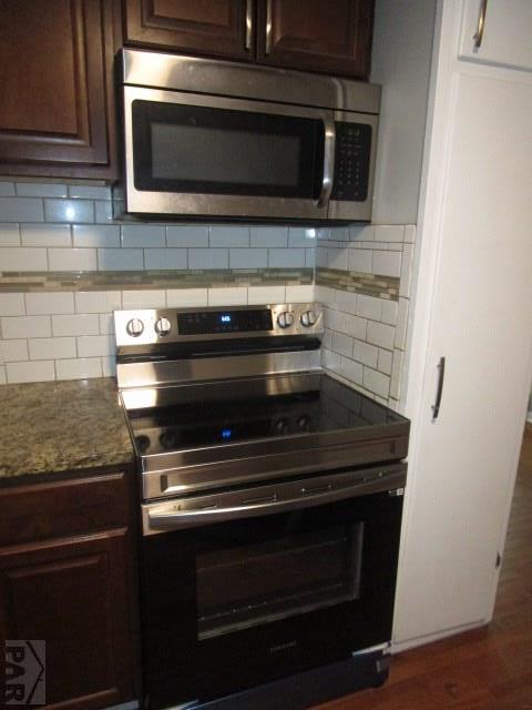 kitchen with appliances with stainless steel finishes, light stone countertops, dark brown cabinetry, and tasteful backsplash