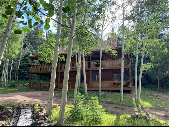 rear view of house featuring a chimney and a wooden deck