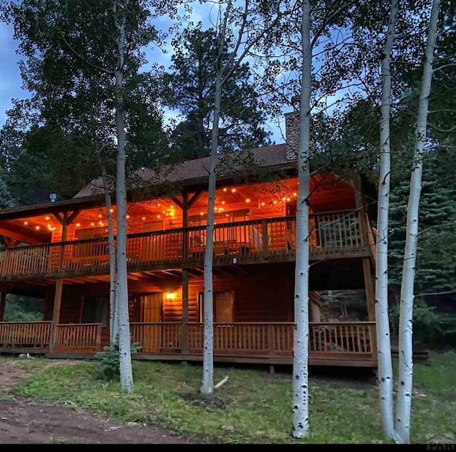 rear view of property featuring a wooden deck and faux log siding