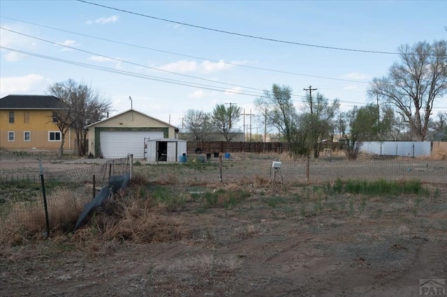 view of yard featuring fence, a detached garage, and an outdoor structure