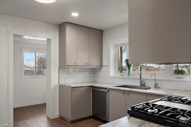 kitchen with a sink, stainless steel dishwasher, wood finished floors, backsplash, and range with gas cooktop