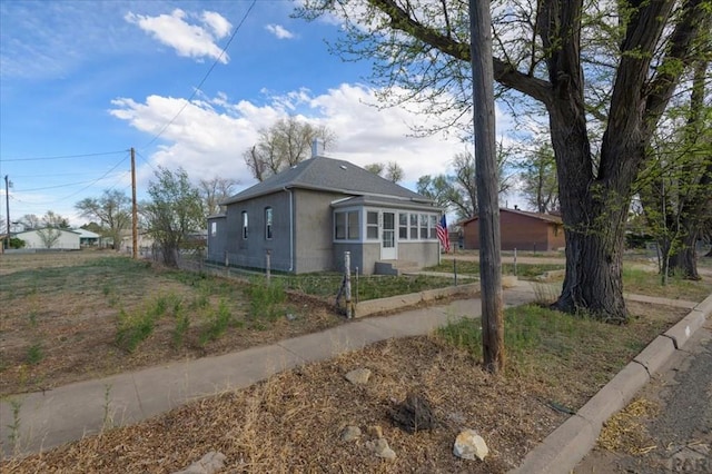 view of side of property featuring stucco siding and fence