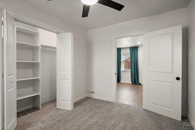 unfurnished bedroom featuring light colored carpet, a ceiling fan, baseboards, and a closet