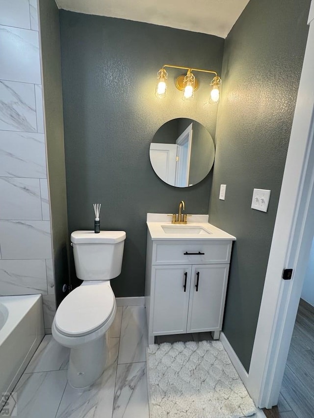 full bathroom with marble finish flooring, baseboards, vanity, a bathtub, and toilet