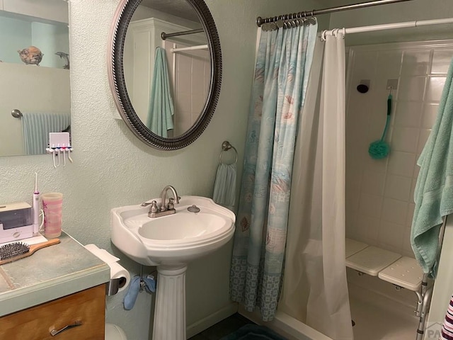 full bath featuring a sink, tiled shower, and a textured wall