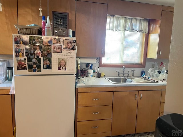 kitchen featuring light countertops, freestanding refrigerator, and a sink