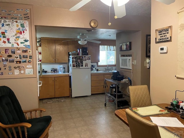 kitchen featuring white appliances, a textured ceiling, a ceiling fan, and a sink