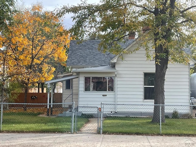 view of home's exterior featuring a fenced front yard, a shingled roof, a yard, and a gate