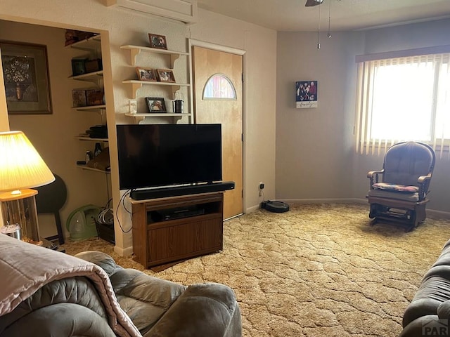 carpeted living room featuring baseboards, ceiling fan, and a wall unit AC
