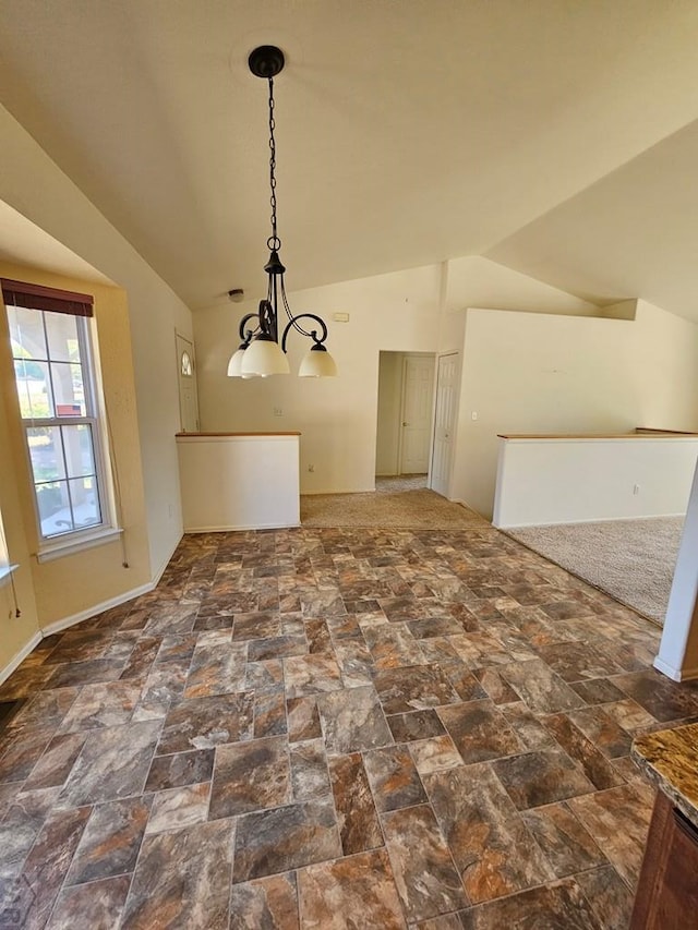 unfurnished dining area featuring an inviting chandelier, stone finish floor, and lofted ceiling