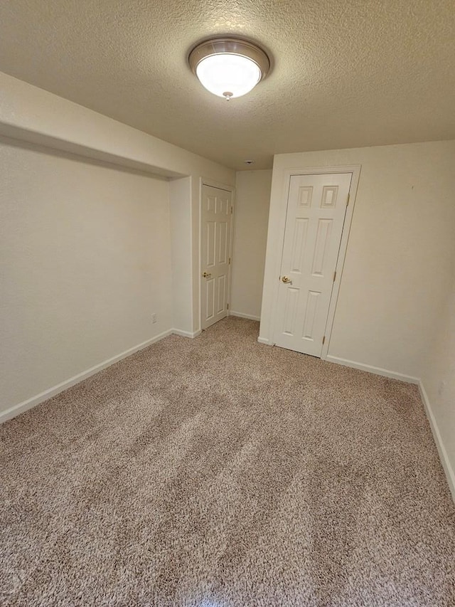 empty room with light carpet, baseboards, and a textured ceiling