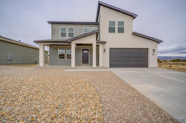 view of front of house featuring an attached garage, covered porch, concrete driveway, and stucco siding