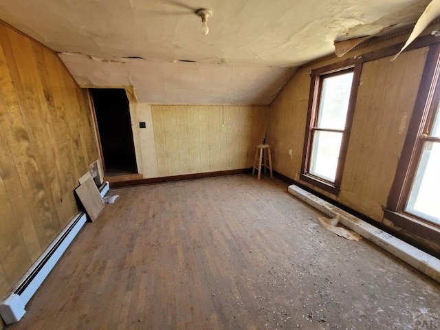 bonus room with baseboards, a baseboard radiator, wood finished floors, vaulted ceiling, and wood walls