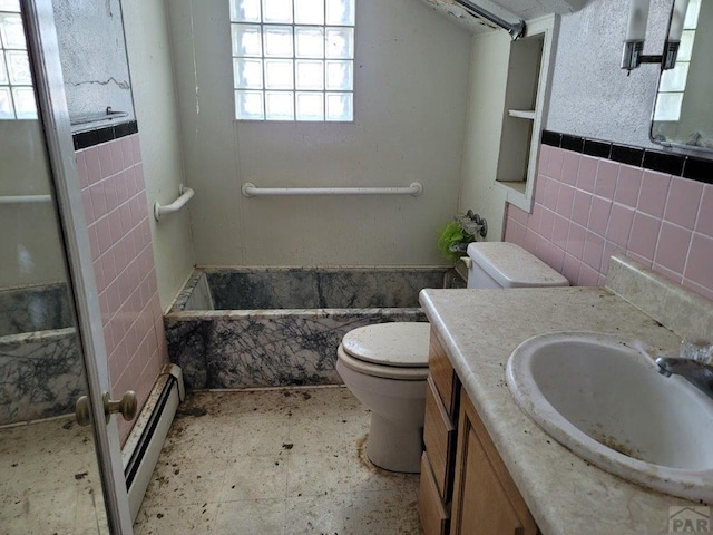 full bathroom featuring a wainscoted wall, tile walls, toilet, a baseboard heating unit, and vanity