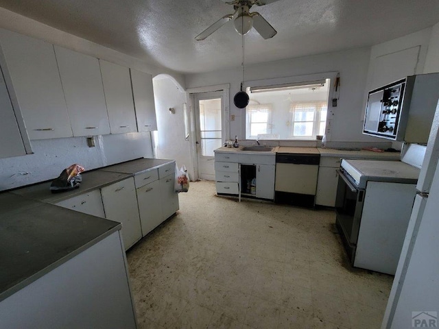 kitchen featuring dark countertops, light floors, white cabinets, and stainless steel dishwasher