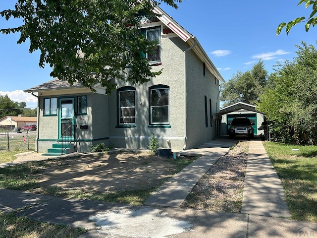 view of front facade featuring a detached carport, fence, and stucco siding
