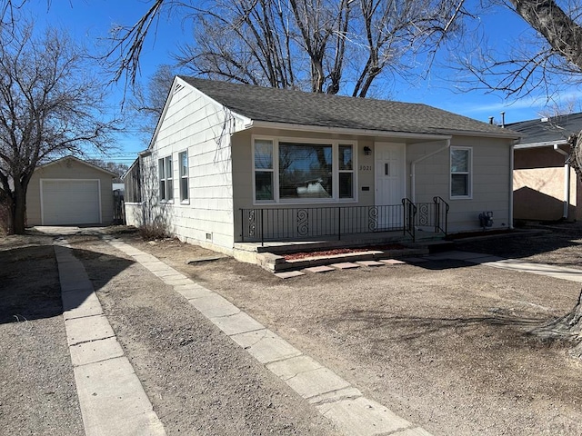 view of front facade with an outbuilding, covered porch, a garage, a shingled roof, and driveway