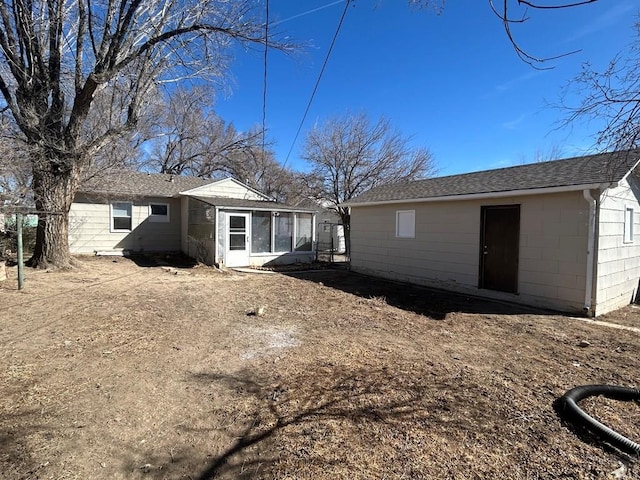 rear view of property featuring an outbuilding and a shingled roof