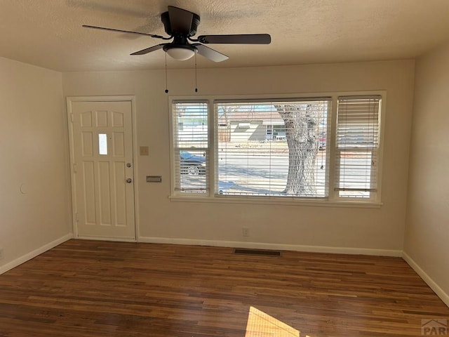 foyer entrance featuring plenty of natural light, a textured ceiling, visible vents, and dark wood-style flooring