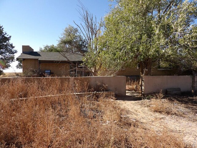 view of home's exterior with a chimney, fence, and brick siding