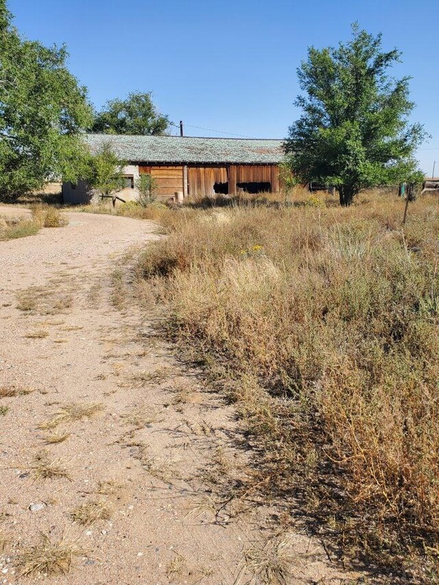 view of side of home featuring dirt driveway and a rural view