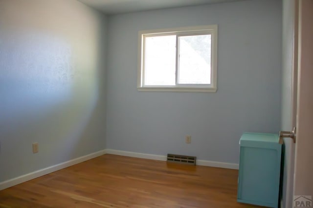 spare room featuring visible vents, light wood-style flooring, and baseboards