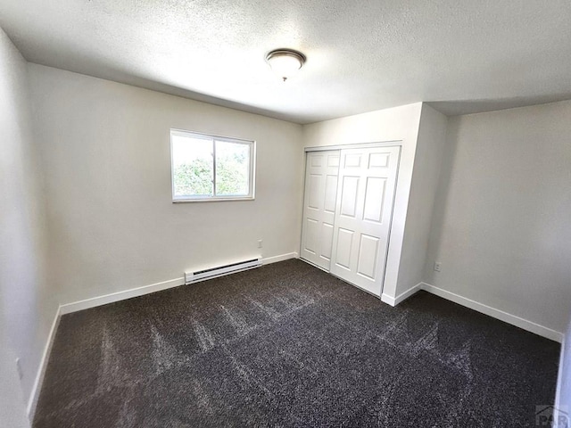 802 E 5th St, Florence, CO 81226 - unfurnished bedroom with a closet, dark colored carpet, baseboards, a textured ceiling, and a baseboard radiator