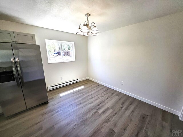 802 E 5th St, Florence, CO 81226 - unfurnished dining area with a baseboard heating unit, dark wood-style floors, an inviting chandelier, and baseboards