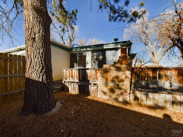 rear view of house featuring fence and stucco siding