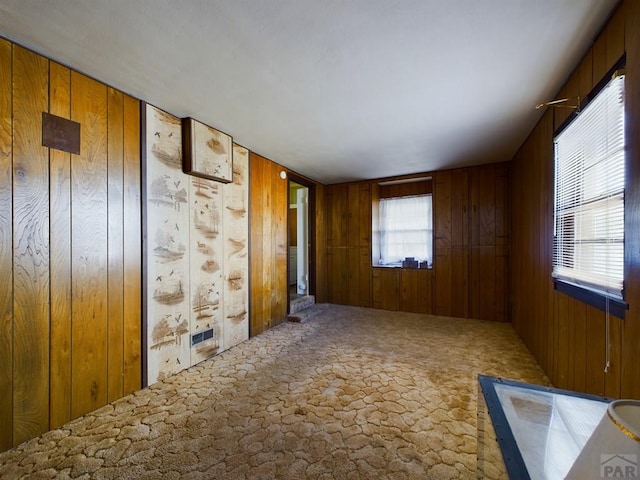 carpeted empty room with wood walls