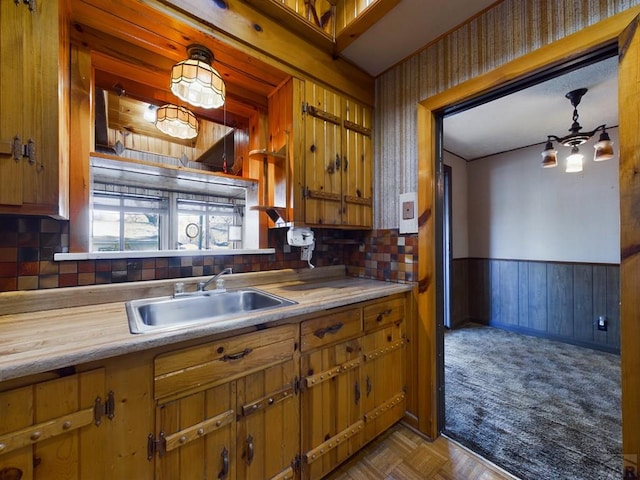 kitchen featuring light countertops, brown cabinetry, a sink, and wainscoting