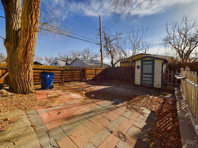 view of patio with an outbuilding, a storage unit, and a fenced backyard