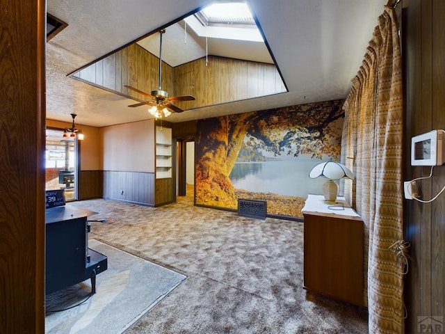 living room with ceiling fan, carpet floors, visible vents, wainscoting, and lofted ceiling with skylight