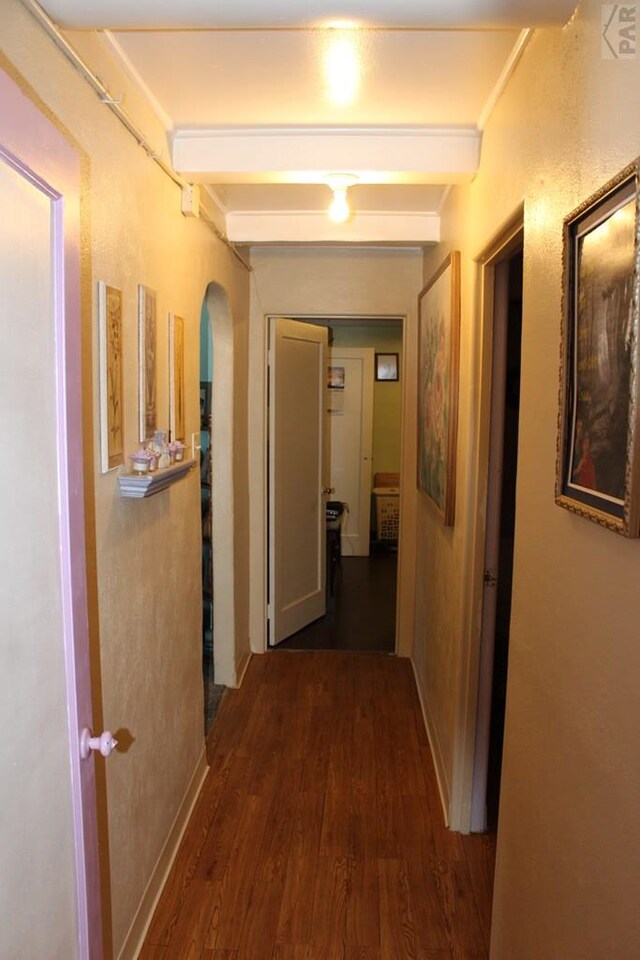 corridor featuring arched walkways, beamed ceiling, and dark wood-style flooring