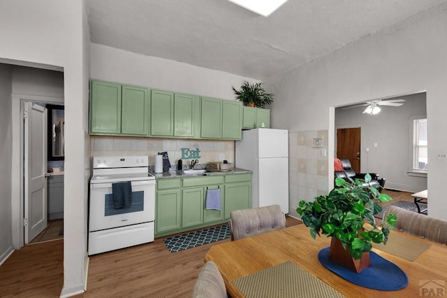 kitchen with tasteful backsplash, green cabinets, white appliances, a sink, and wood finished floors