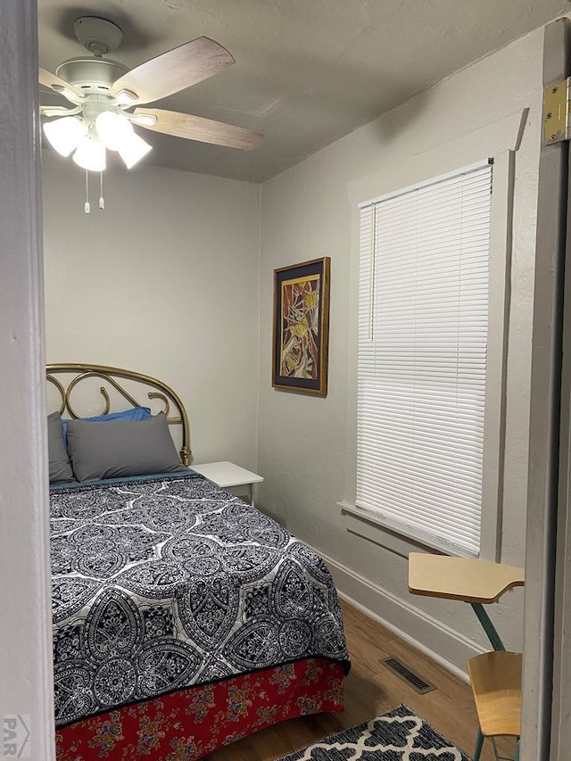 bedroom featuring wood finished floors, ceiling fan, baseboards, and visible vents