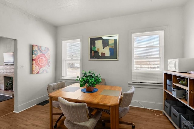 dining area featuring wood finished floors, a fireplace, and baseboards